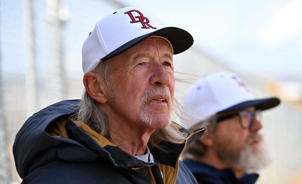 Pitching coach Rick Fisher, left, watches the pitcher and catcher from near the dugout as the team's game against Columbine gets underway at Easton Fields in Littleton, Colorado, on April 1, 2025. (Photo by Helen H. Richardson/The Denver Post)