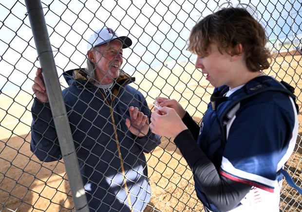 Pitching coach Rick Fisher has a lighthearted moment with catcher Ryan Morris, right, as he reads the small comic inside a bubble gum wrapper during a break in their game against Columbine at Easton Fields in Littleton, Colorado, on April 1, 2025. (Photo by Helen H. Richardson/The Denver Post)