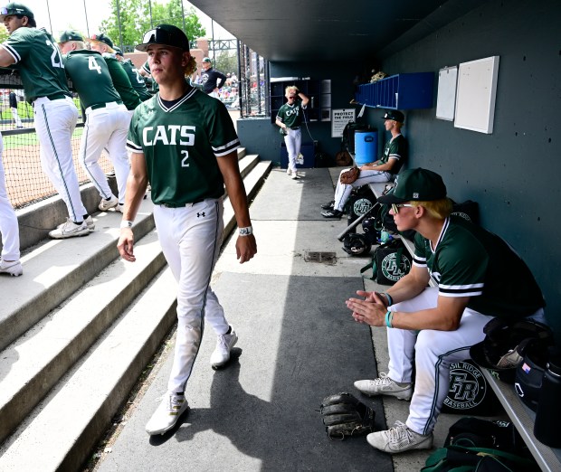 Fossil Ridge baseball player Mason Griffin, left, (2), walks past teammate Owen Morgan, right, (22) in the dugout before the class 5A state baseball tournament game against the Broomfield Eagles at All-Star Park in Lakewood, Colorado on Friday, May 23, 2025. (Photo by Andy Cross/The Denver Post)