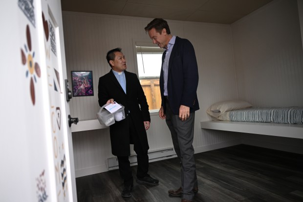 Father Joseph Dang, left, shows Denver Mayor Mike Johnston a welcome kit for each resident that is inside each of the new tiny homes at the new Overland Park micro-community in Denver on March 11, 2024. This long-in-the works micro community on CDOT land in far southern Denver is the continuation and re-naming of Johnston's House 1,000 homelessness Initiative from last year. The program is now called All In Mile High with aims to bring another 1,000 people off the streets in 2024. The micro-community in the Overland Park neighborhood includes 60 individual indoor and will provide wraparound services to residents. During the same week, outreach teams will engage people living outdoors to offer them indoor accommodations, connections to a suite of wraparound services, and a pathway toward permanent housing. People from the selected encampment will be moved to the Overland Park micro-community, while others will be offered indoor accommodations at other sites...The opening of the Overland Park micro-community and upcoming encampment resolution will mark the first major milestone of All In Mile High, one of Mayor Johnston's 2024 citywide goals. All In Mile High focuses on increasing the total number of people brought indoors from unsheltered homelessness to 2,000 by Dec. 31, 2024 and is the long-term name for the House1000 initiative that launched in 2023. The initiative aligns with Mayor Johnston's vision to bringing those experiencing homelessness indoors and improving access to supportive services like mental health treatment, drug rehabilitation, and job training programs. (Photo by Helen H. Richardson/The Denver Post)
