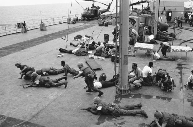 FILE- U.S. Marines hit the deck of the USS Blue Ridge to dodge flying metal from a South Vietnamese helicopter that crashed on the deck of the ship, April 29, 1975. One pilot had dropped his helicopter on the blade of another that had just landed, and chunks of metal ripped through the air. The top helicopter, with its load of women and children, nearly toppled into the sea, but they were rescued and there were no injuries. (AP Photo/J.T. Wolkerstorfer, File)
