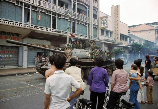 FILE- Victorious North Vietnamese troops ride a tank down Rue Catinat in Saigon while South Vietnamese civilians look on, April 30, 1975, as the capital of South Vietnam fell to communist forces, ending the Vietnam War. (AP Photo/Yves Billy, File)
