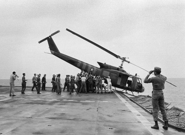 FILE- U.S. Navy personnel aboard the USS Blue Ridge push a helicopter into the sea off the coast of Vietnam in order to make room for more evacuation flights from Saigon, Tuesday, April 29, 1975. The helicopter had carried Vietnamese fleeing Saigon as North Vietnamese forces closed in on the capital. (AP Photo/jt, File)